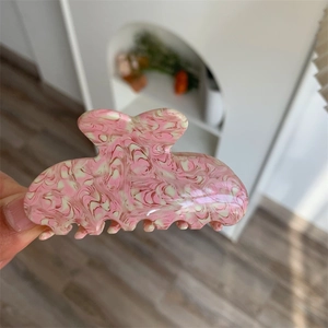 Close-up of pink peach blossom marble texture on acetate hair claw clip held in hand