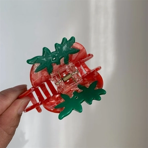 Detail of a medium acetate strawberry hair claw clip featuring red and green resin texture