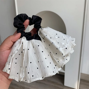 Close-up of black and white lace scrunchie with polka dots and embroidery detail