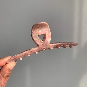 Detail shot of a pink marble textured acetate claw clip with a glossy finish for women