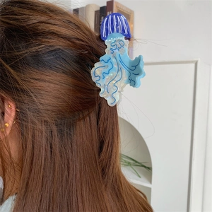 Dettaglio della molletta per capelli a medusa in acetato blu e bianco su capelli castani