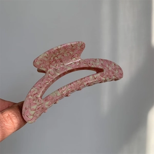 Detail of pink and white marble texture acetate hair claw clip held in hand