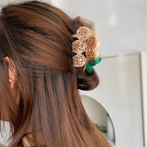 Detail view of the acetate hair claw clip featuring natural textures and leaf design