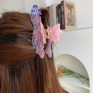 Dettaglio di una molletta per capelli a forma di medusa viola sfumata indossata sui capelli