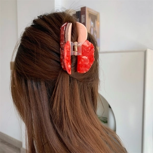 Detail of a red marble acetate strawberry hair claw clip worn in a half-up hairstyle