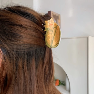 Detail of tulip acetate hair claw clip with floral patterns on brown hair side view
