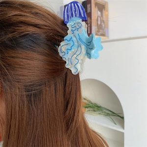 Dettaglio di un fermaglio per capelli in acetato a forma di medusa su capelli castani