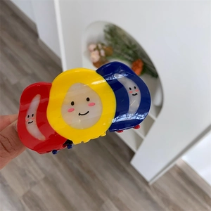 Close-up of colorful acetate claw clip with red, yellow, and blue smiley face design