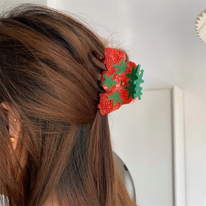 Detail of realistic strawberry claw clip worn on brown hair for sweet style