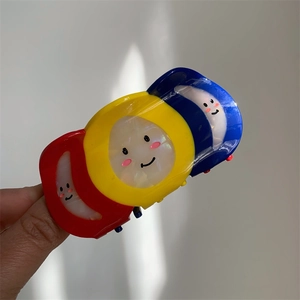 Detail of creative colorful acetate hair claw clip with smiling face design held by hand