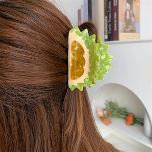Detailed view of a creative durian-shaped acetate hair claw clip on brunette hair