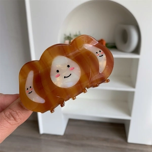 Detailed macro view of an amber marble acetate hair claw clip with smiling face patterns