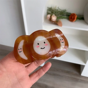 Close-up of translucent amber acetate hair claw clip with creative smiley face design