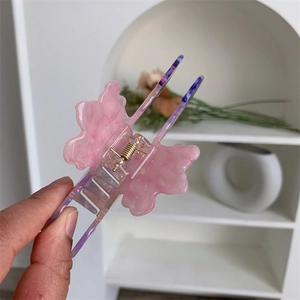 Dettaglio di un fermaglio per capelli in acetato marmorizzato rosa e viola a medusa