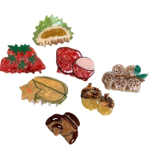 Creative acetate hair claws in fruit shapes like durian and strawberry on white background
