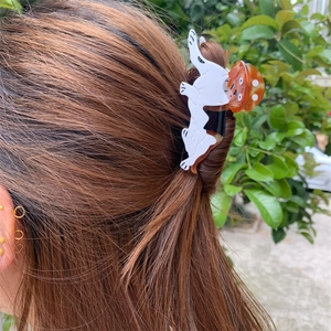 Detailed view of a small dog-shaped acetate hair claw clip worn on long brown hair