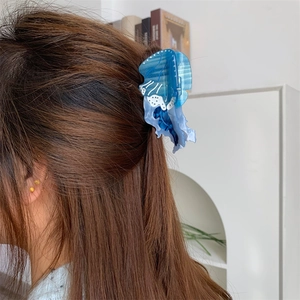 Dettaglio di una molletta per capelli a medusa blu traslucida su capelli lunghi