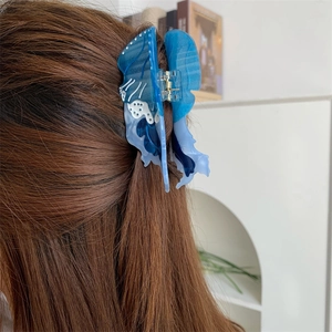 Dettaglio della molletta per capelli a medusa blu sfumato in un contesto di stile
