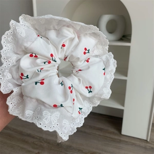Dettaglio dell'elastico in pizzo bianco con stampa a ciliegie rosse e bordi raffinati