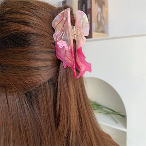 Pinza per capelli a farfalla in acetato rosa indossata su capelli lunghi, vista da dietro