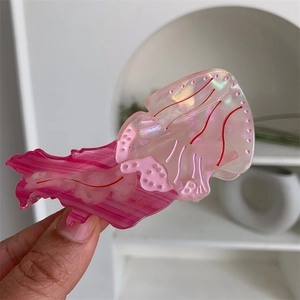 Dettaglio di un fermaglio per capelli a forma di medusa con strisce rosa e perlacee