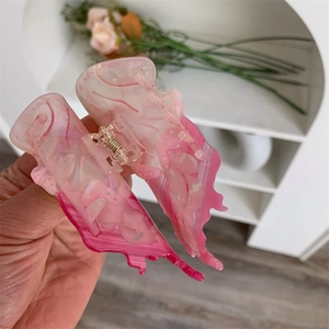 Dettaglio di una molletta per capelli a farfalla in acetato con sfumatura rosa chic
