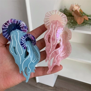 Dettaglio di due mollette per capelli a forma di medusa in acetato blu e rosa traslucido