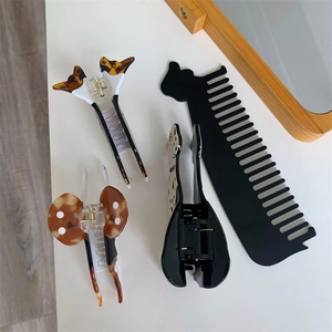 Detail of acetate animal print hair claws and black cat ear comb set on white surface