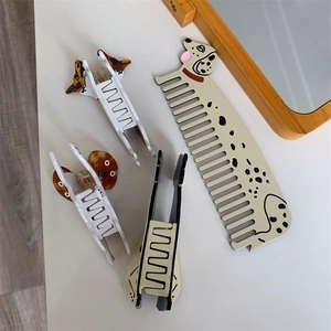 Creative dalmatian dog hair comb and assorted acetate claw clips on white surface