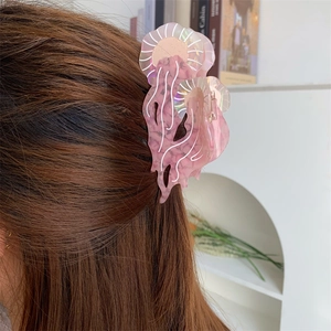 Dettaglio della molletta per capelli a medusa rosa in acetato su capelli castani