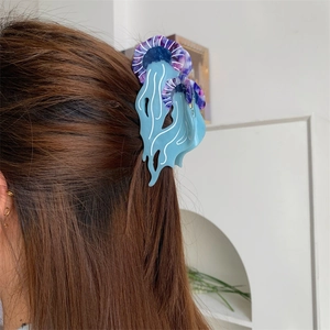 Vista dettagliata di una molletta per capelli a medusa in acetato blu su capelli castani