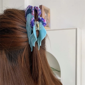 Dettaglio della molletta per capelli a farfalla in acetato blu e trama lucida