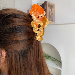 Dettaglio della molletta per capelli a medusa in acetato su lunghi capelli biondi