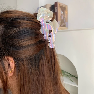 Dettaglio di un fermaglio per capelli in acetato a righe su lunghi capelli castani