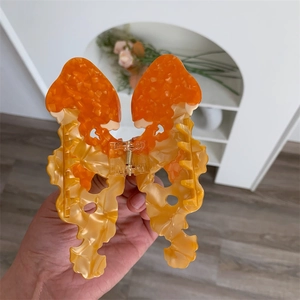 Dettaglio ravvicinato di un fermaglio per capelli in acetato marmorizzato arancione