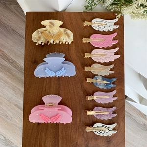 Makroaufnahme von Acetat-Haarklammern und Engelsflügel-Haarnadeln auf Holzdisplay