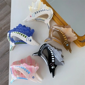 Detailed view of fish-shaped acetate hair claws in five marble-textured colors