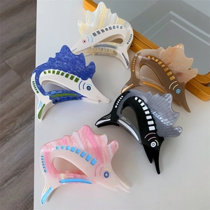 Detailed close-up showing five colorful swordfish-shaped acetate hair claws on a table
