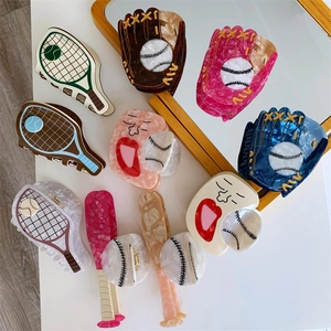 Detail showing acetate hair claws with creative tennis racket and baseball glove shapes