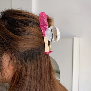 Detail view of a rose red baseball bat hair claw clip styled on a model ponytail