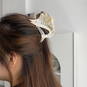 Detail of fish-shaped acetate hair claw clip worn on hair showing marble texture