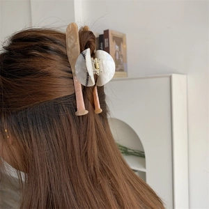 Detail view of a creative acetate baseball and bat hair claw clip in dark hair