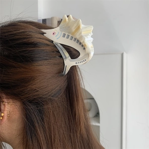 Detailed view of the fish-shaped acetate hair claw clip styled on dark brown long hair
