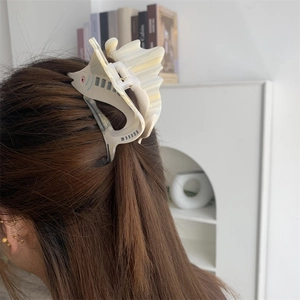 Detailed view of the sailfish-shaped acetate hair claw clip worn on long brown hair