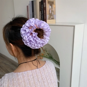 Chic purple pleated fabric scrunchie with layered ruffle design on messy hair bun