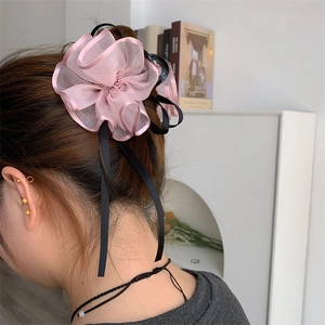 Vista dettagliata di un fermaglio per capelli a fiore in organza rosa con nastro nero