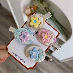 Dettaglio di quattro mollette floreali color caramello in rosa, blu, giallo e verde