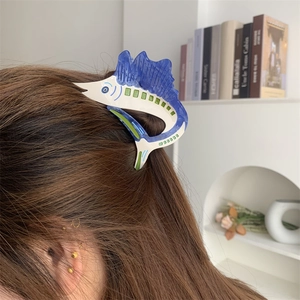 Detail of a sailfish shaped acetate hair claw clip worn on long hair for a stylish look