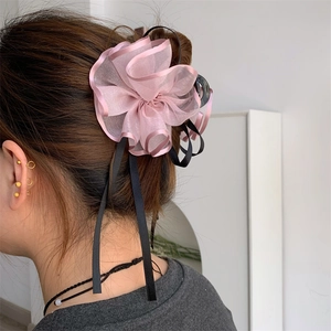 Dettaglio della molletta per capelli con fiore di organza rosa e nastri neri