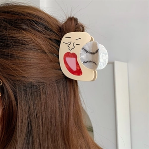 Creative acetate hair claw clip with unique facial pattern on dark brown hair